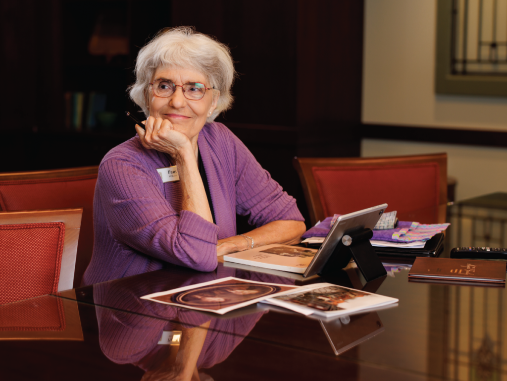 Pam sitting at a desk with her laptop and books