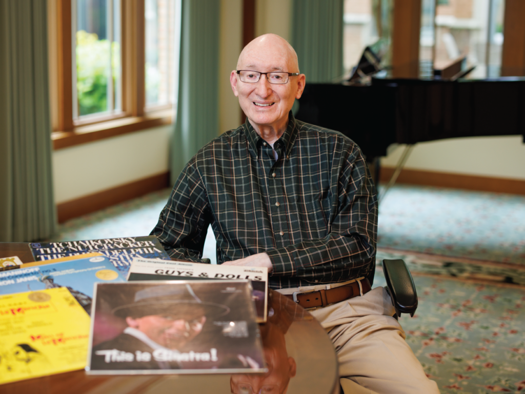 Bruce sitting in front of his piano with sheet music on the table in front of him